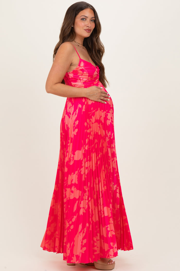 woman wearing a bright pink floral printed maternity maxi dress and holding her baby bump