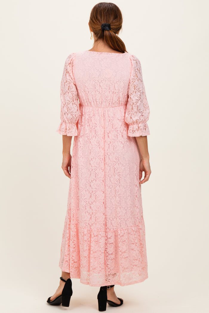 woman wearing a light pink lace maxi dress with puff sleeves and a tiered hem, viewed from the back