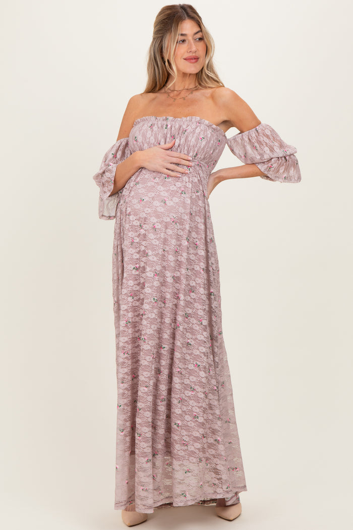 woman wearing a floral off-the-shoulder long pink maternity dress and holding her baby bump