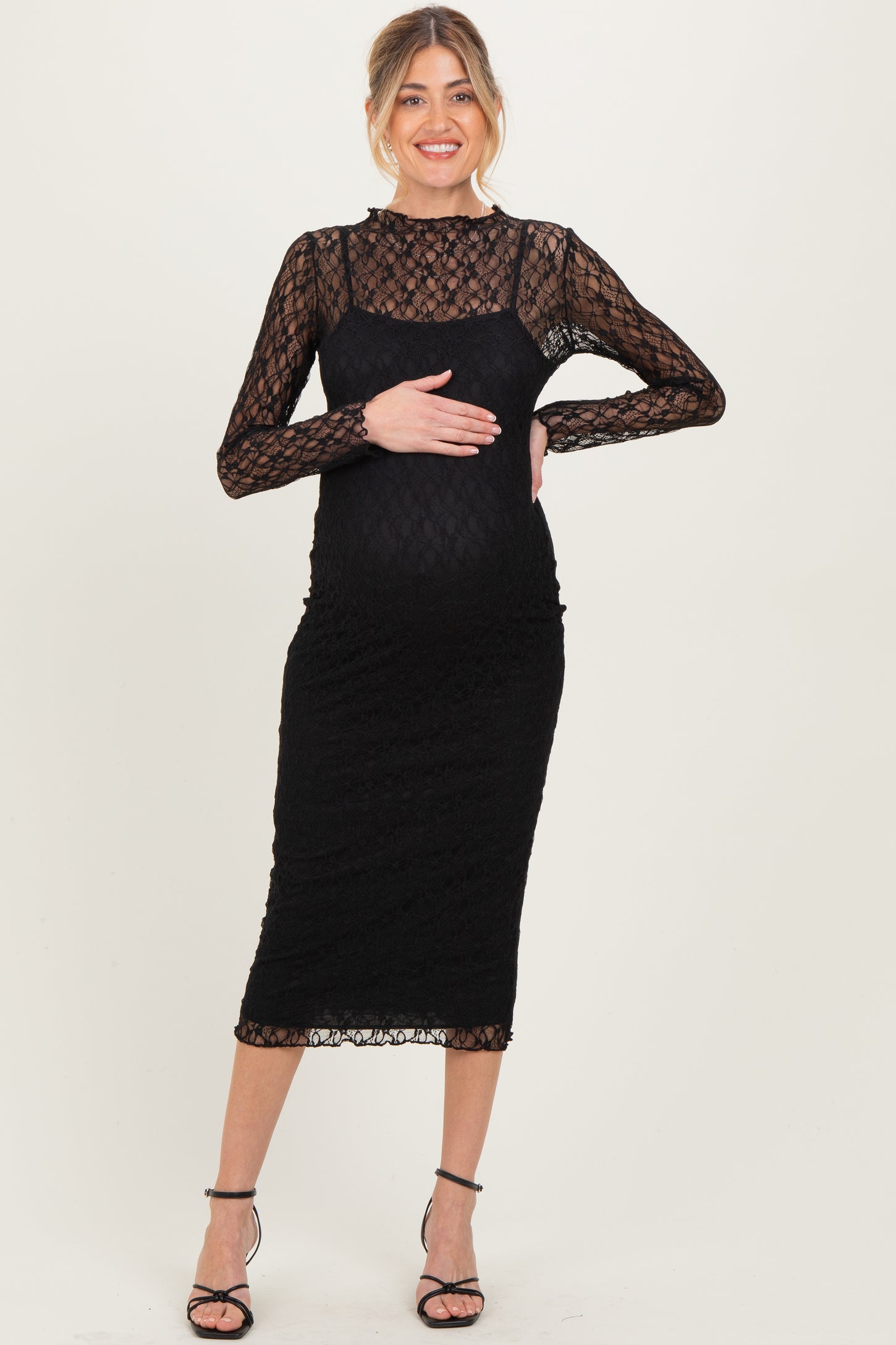 woman wearing a black lace long sleeve maternity dress and holding her baby bump