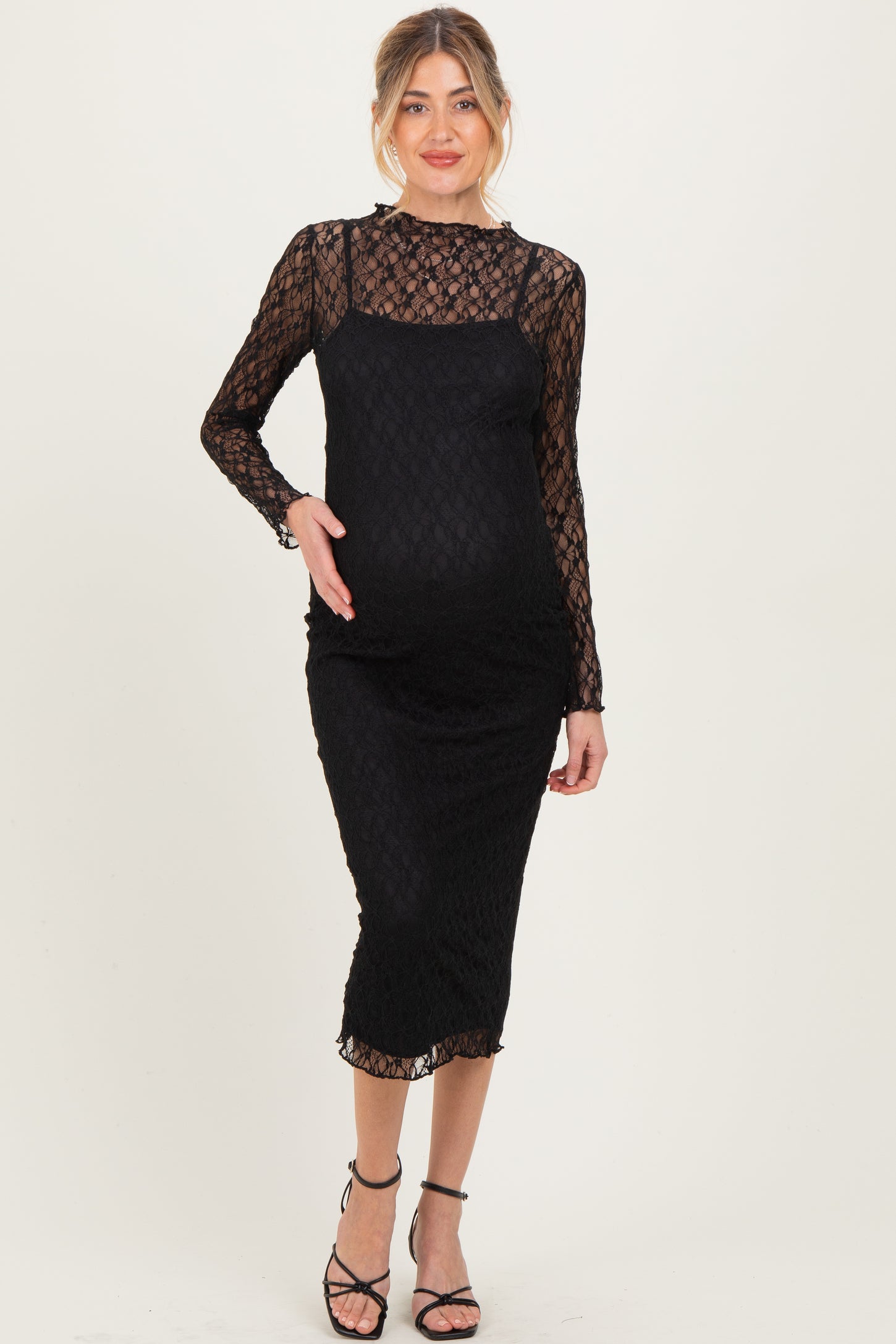 woman wearing a black lace long sleeve maternity dress that hugs her baby bump
