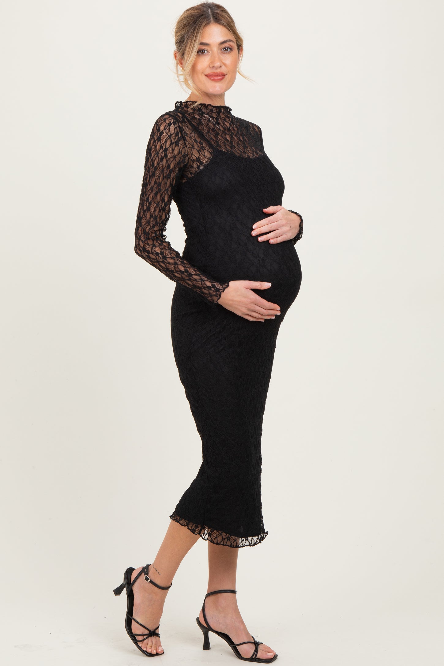 woman wearing a black lace maternity dress with long sleeves and a fitted silhouette, highlighting her baby bump