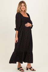 woman wearing a black floral print maternity maxi dress with a square neckline and ruffled sleeves, showing her baby bump