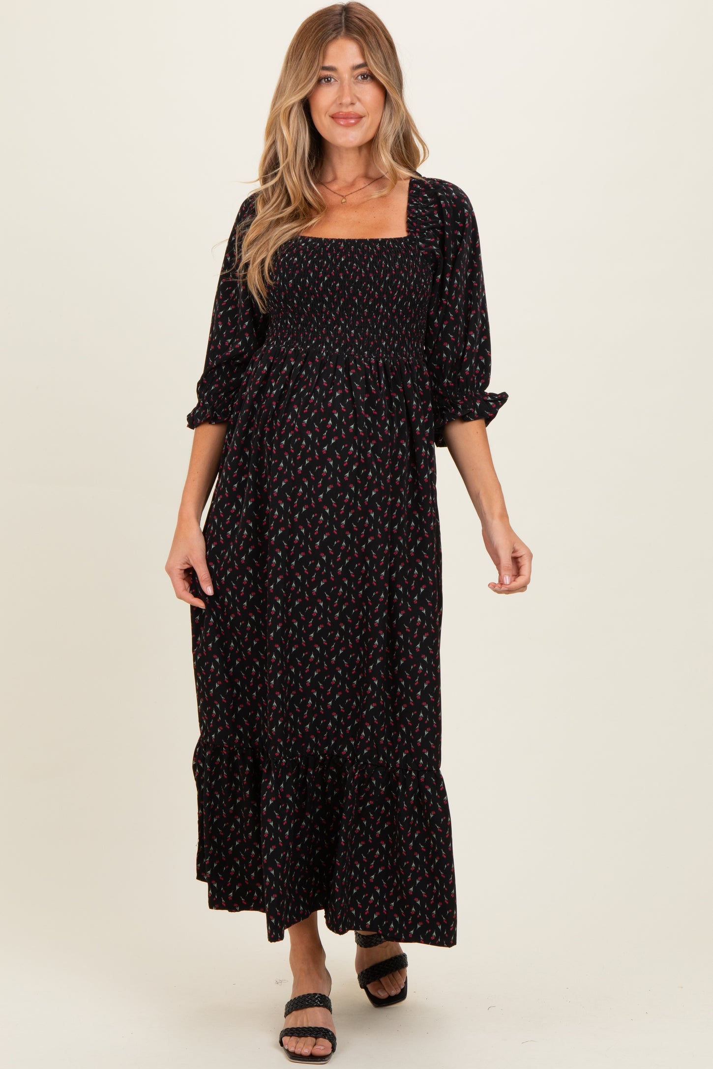 woman wearing a black floral maternity dress with puff sleeves and a ruffled hem, showing her baby bump