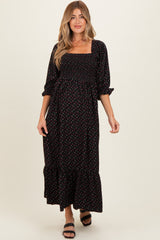 woman wearing a black floral maternity dress with puff sleeves and a ruffled hem, showing her baby bump