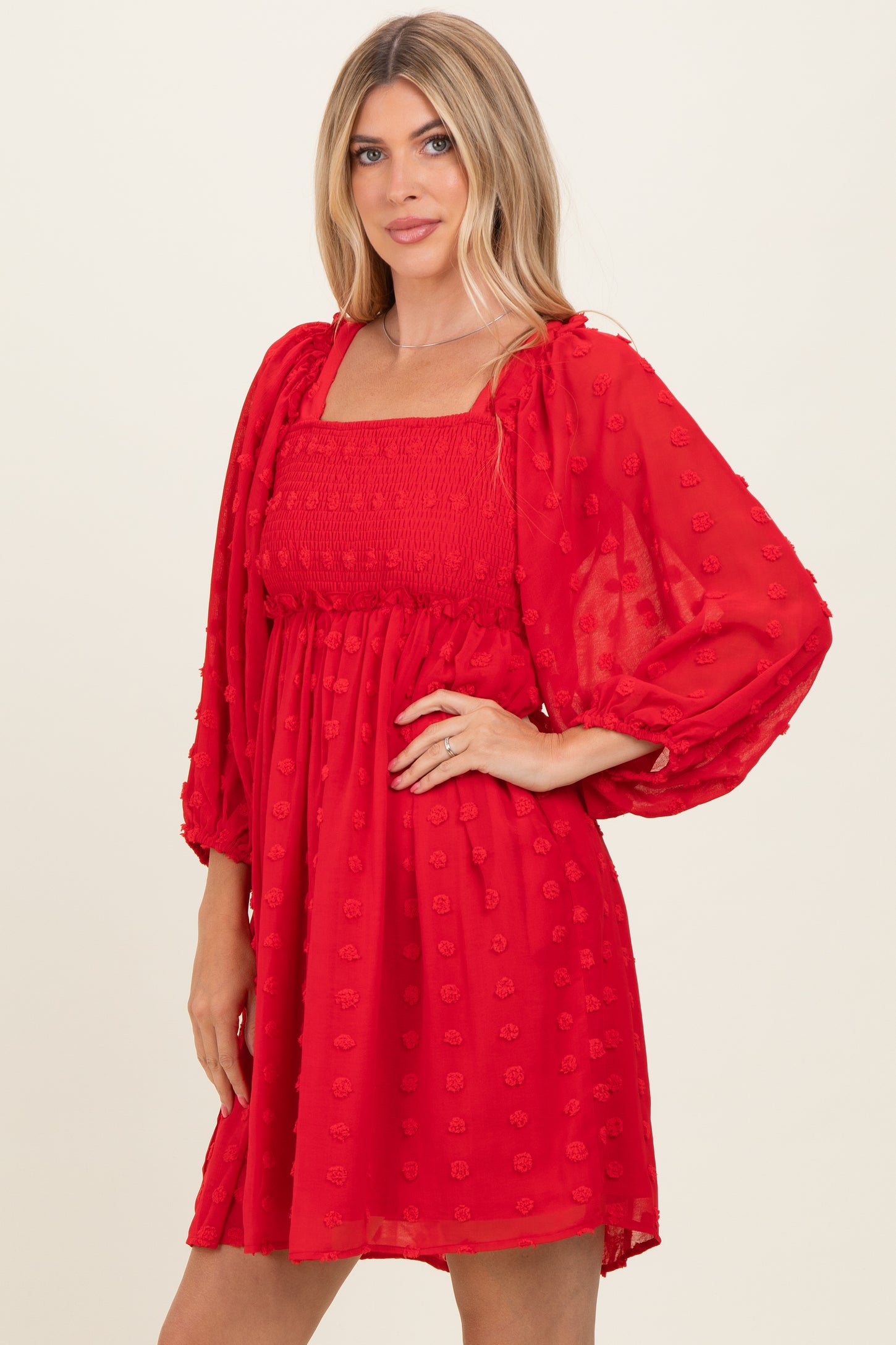 woman wearing a red puff sleeve mini dress with a square neckline and textured floral details