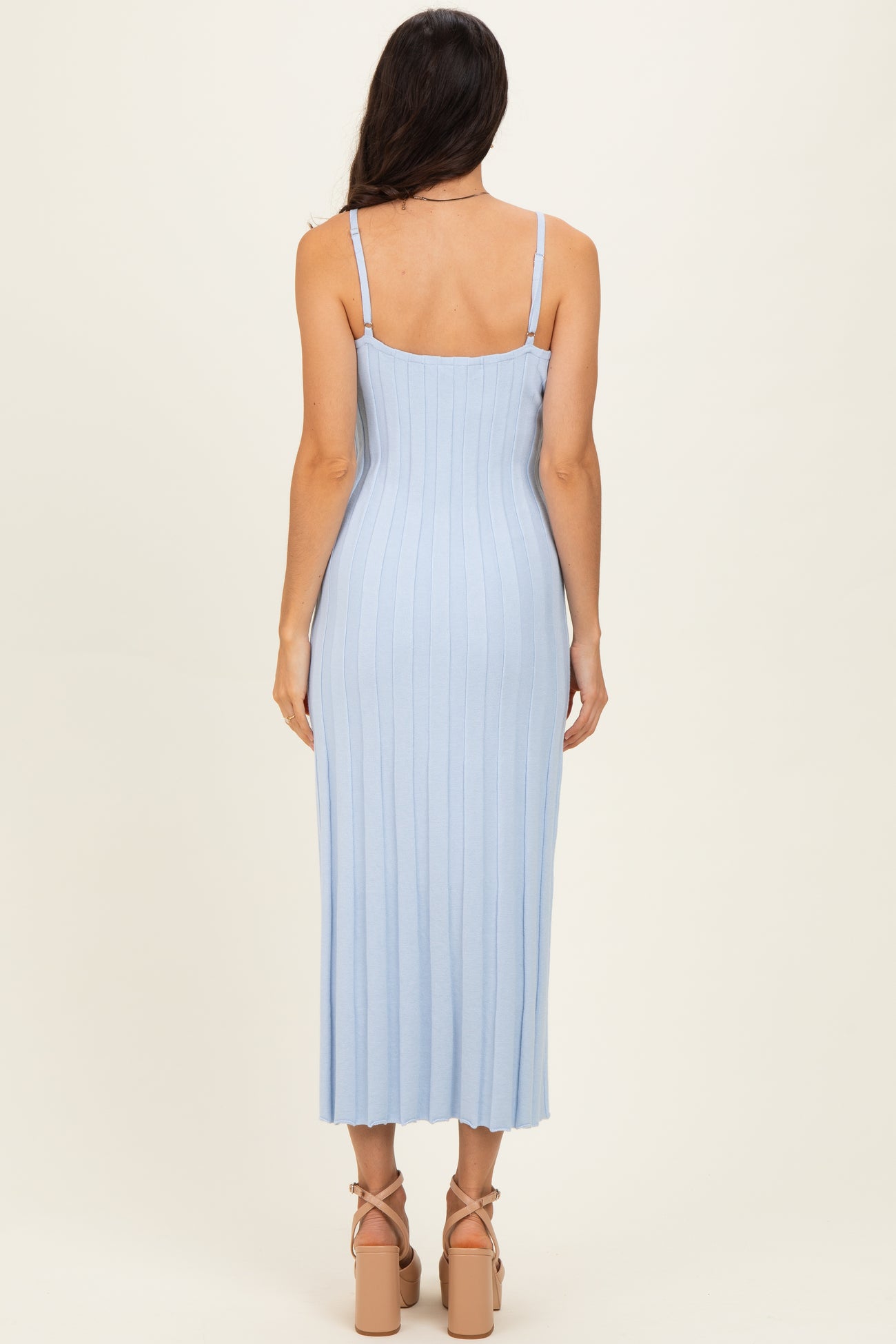 woman wearing a light blue ribbed midi dress with adjustable straps and a fitted silhouette, viewed from the back