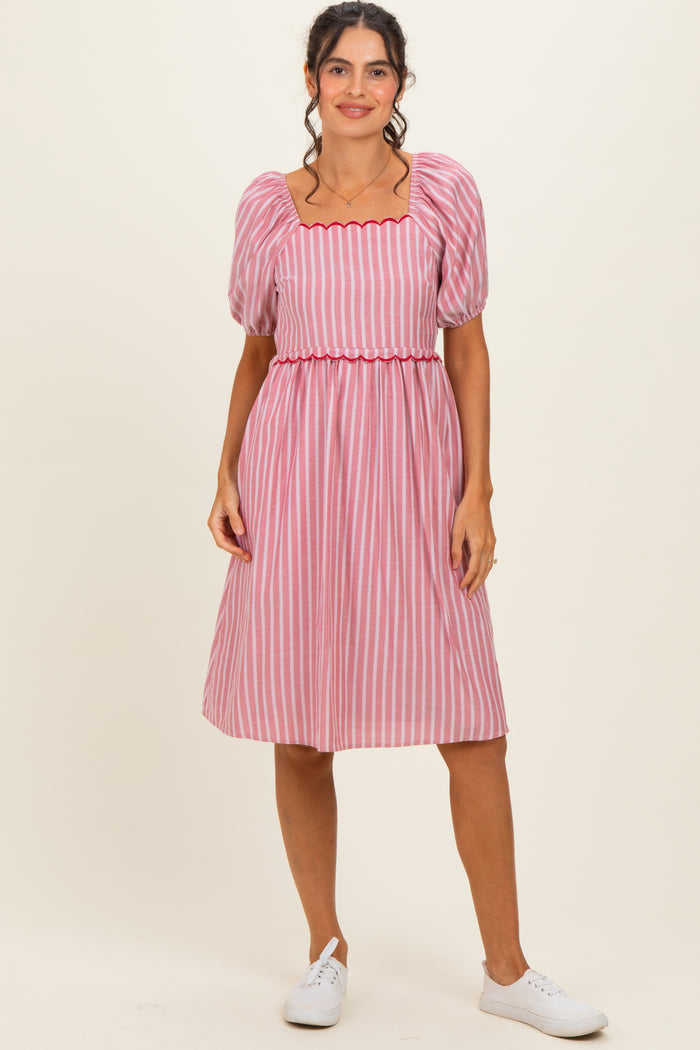 woman wearing a pink and white striped midi dress with puff sleeves and a fitted waist