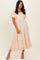 woman wearing a light orange gingham print maxi dress with short puff sleeves and a tiered hemline