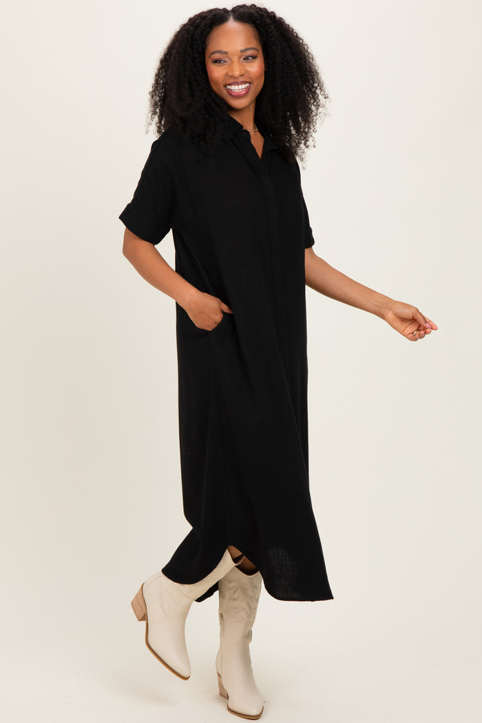 woman wearing a black short sleeve button-up maxi dress with side pockets and beige ankle booties