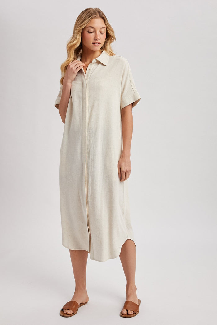 woman wearing a beige short sleeve button-up midi dress and brown sandals