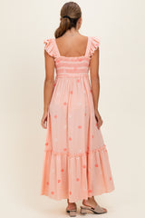 woman wearing a pink floral maxi dress with ruffle straps and tiered hem, seen from the back