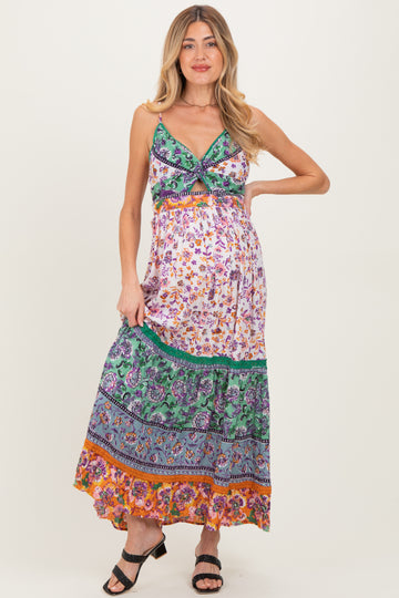 woman wearing a colorful maxi maternity dress with floral patterns and a fitted bodice, showcasing her baby bump