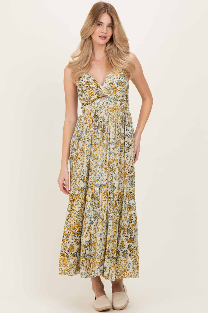 woman wearing a floral maxi dress with a deep v-neckline and pleated skirt, standing against a light background