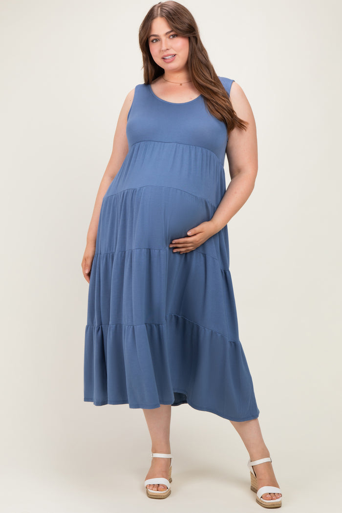 woman wearing a blue sleeveless maternity plus dress with tiered layers and holding her baby bump