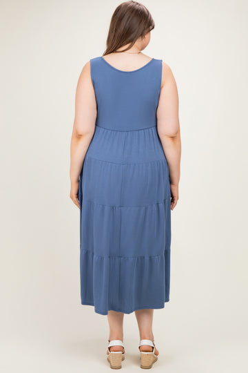 woman wearing a blue maternity plus tiered maxi dress, shown from the back with no visible baby bump