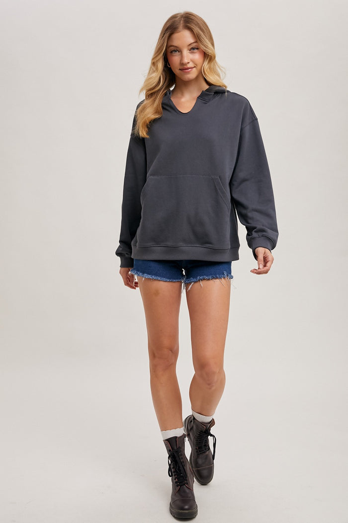 woman wearing a charcoal gray oversized hoodie with a front pocket and distressed denim shorts