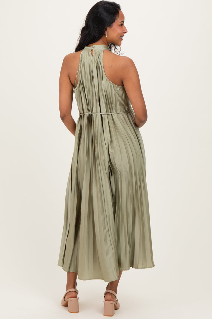 woman wearing a flowy olive green maternity dress with pleated details and open back, showing her baby bump