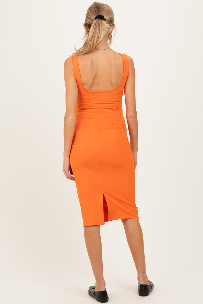 woman wearing a vibrant orange maternity dress with a fitted silhouette and a back slit, showing a smooth back design
