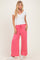 woman wearing a white short sleeve v-neck top and pink wide leg pants with a drawstring waist and side pocket
