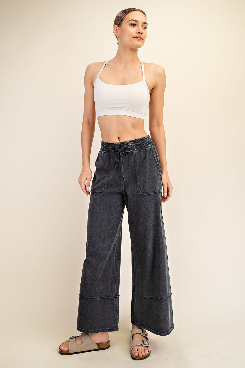 woman wearing a white cropped tank top and grey wide-leg pants with pockets