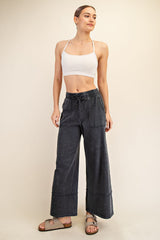 woman wearing a white cropped tank top and grey wide-leg pants with pockets