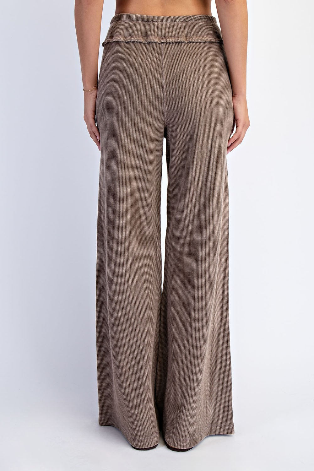 woman wearing brown ribbed wide-leg pants with a ruffled waistband, viewed from the back