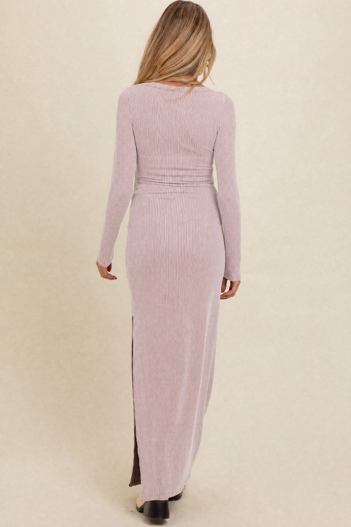 woman wearing a light pink ribbed long sleeve maternity dress with a side slit, showing her back