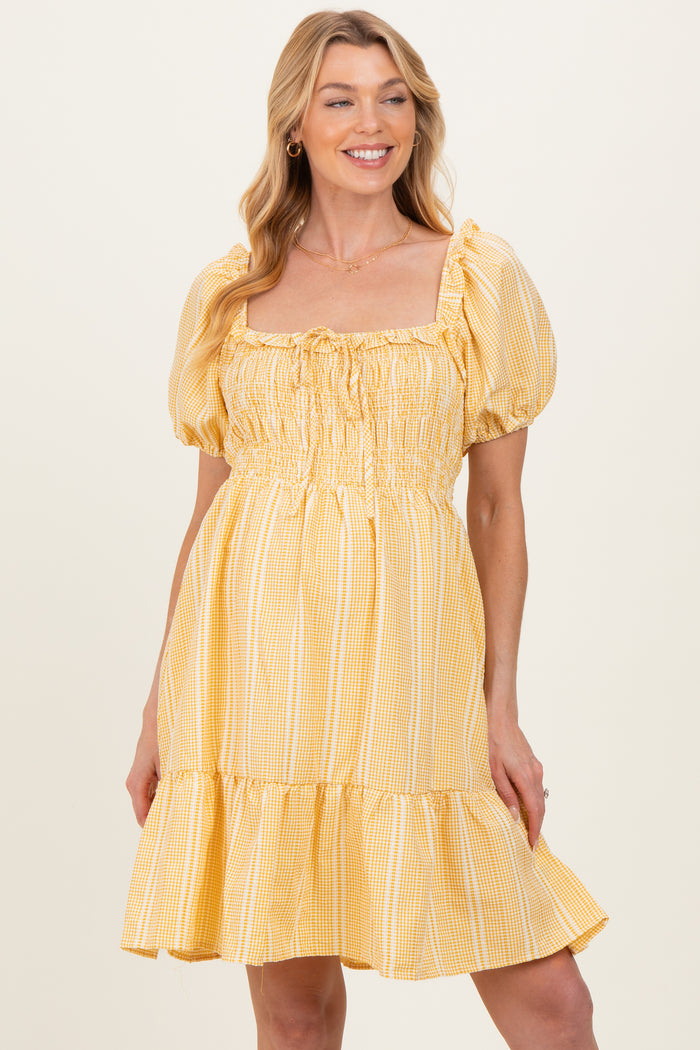 woman wearing a yellow gingham maternity dress with puff sleeves and a gathered waistline