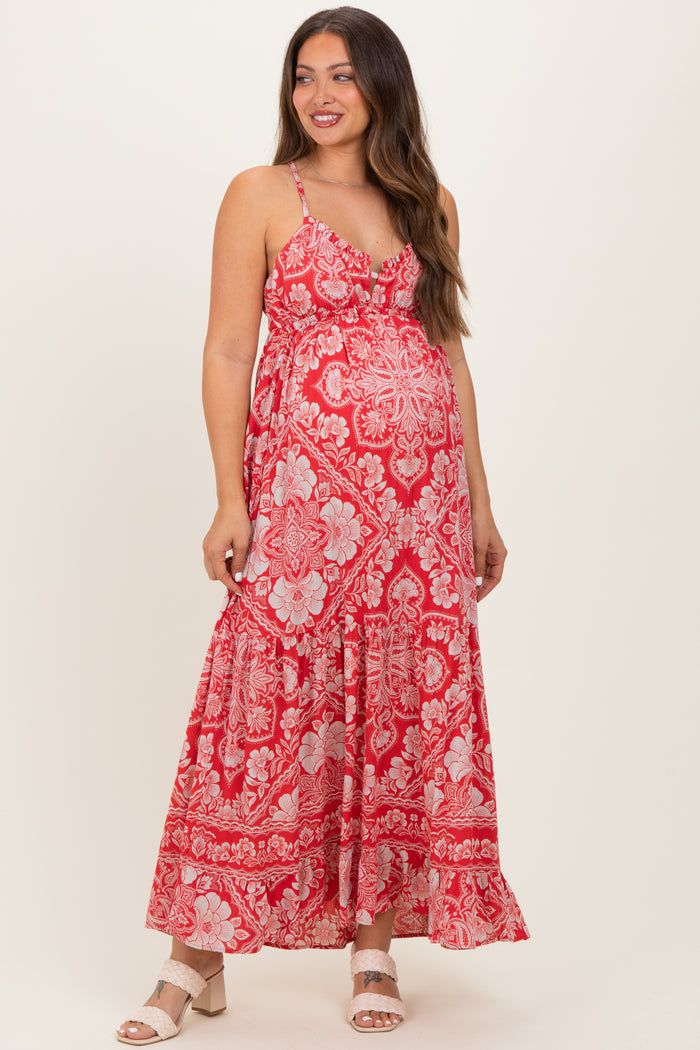 woman wearing a red floral maternity maxi dress with adjustable straps and a flowing skirt, showcasing her baby bump