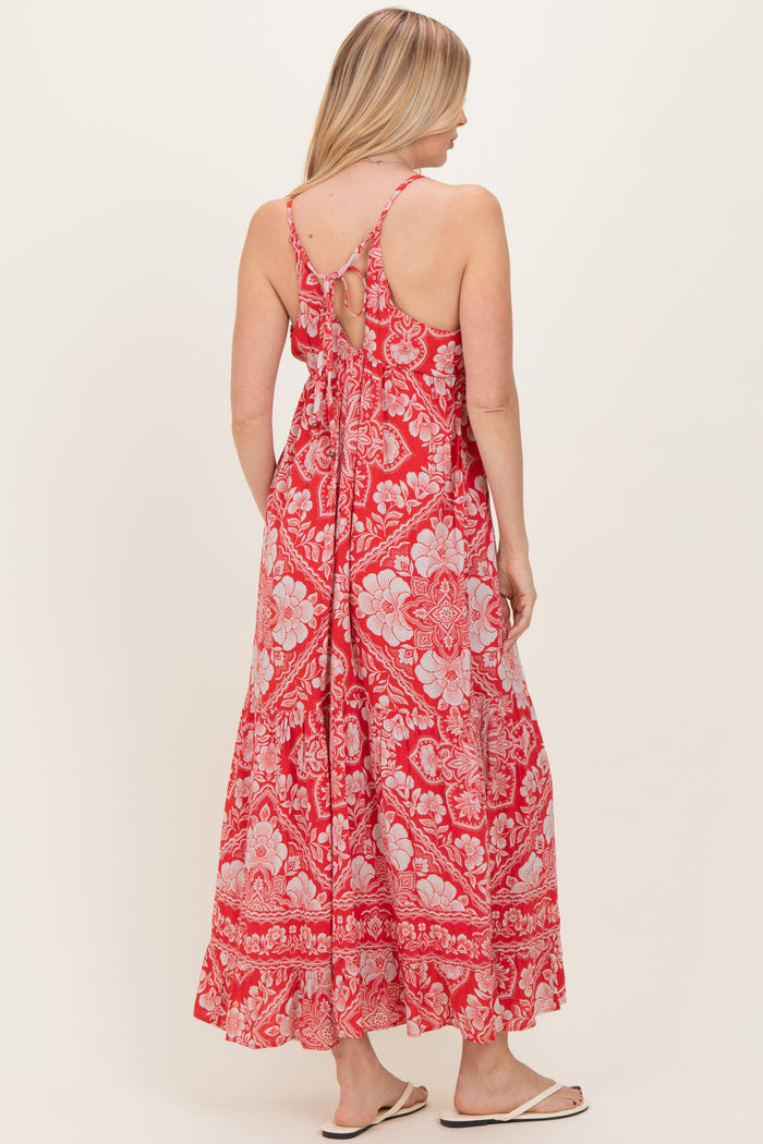 woman wearing a red floral maxi dress with a tie back and adjustable straps, showing the back view