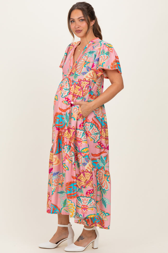 woman wearing a pink floral maternity maxi dress with pockets and short sleeves, showing her baby bump