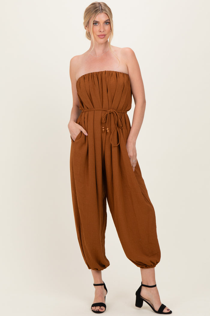 woman wearing a strapless brown jumpsuit with a drawstring waist and side pockets