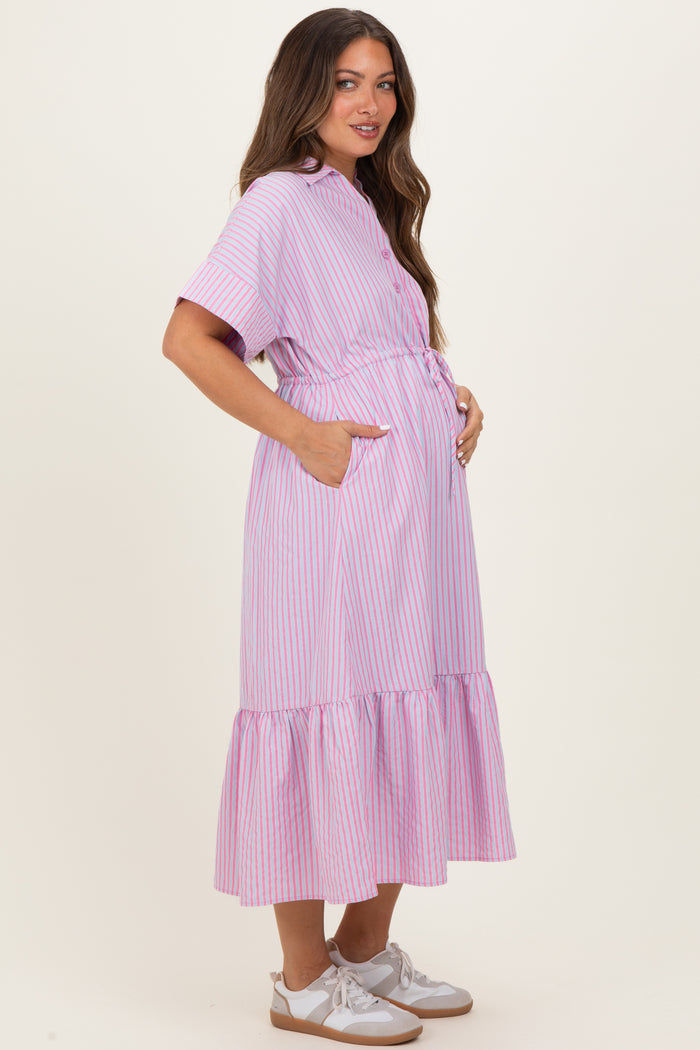 woman wearing a pink and white striped maternity dress with a ruffled hem and pockets, holding her baby bump