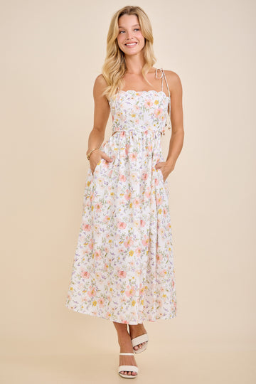 woman wearing a white floral maxi dress with adjustable straps and pockets