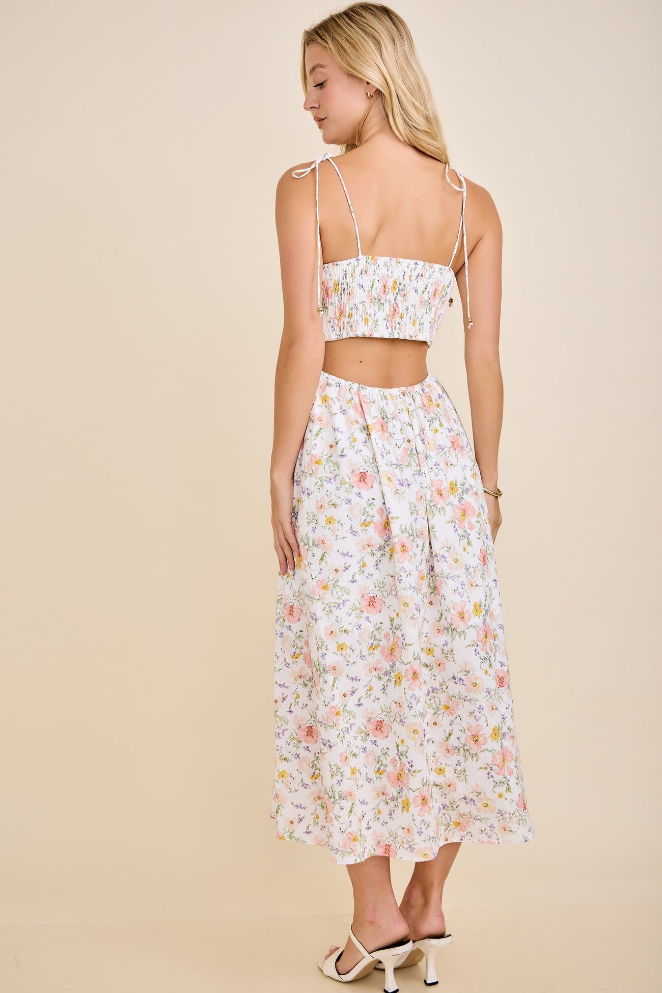 woman wearing a white floral crop top and matching maxi skirt with tied shoulder straps and a gathered back