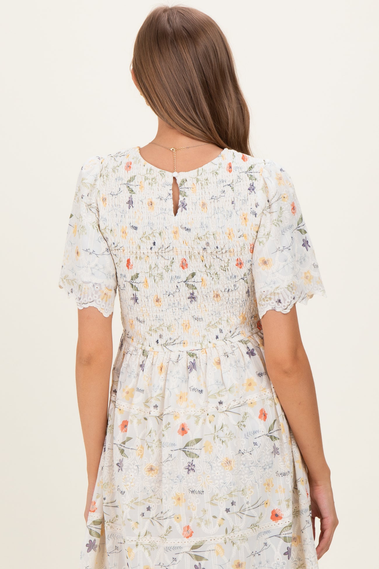 woman wearing a floral maternity dress with short sleeves and a smocked back detail