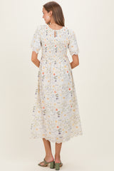 woman wearing a floral print maternity dress with short puff sleeves and a smocked back detail
