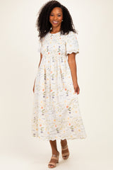 woman wearing a white floral midi dress with short puff sleeves and a gathered waist, smiling at the camera