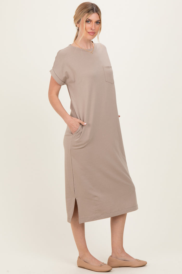 woman wearing a beige short sleeve midi dress with a pocket and side slits, standing with hands in pockets