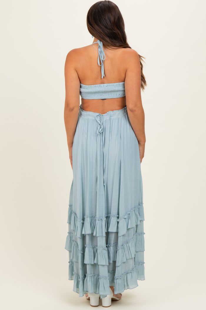 woman wearing a light blue maternity maxi dress with ruffled layers and a halter neck design, showing off a baby bump
