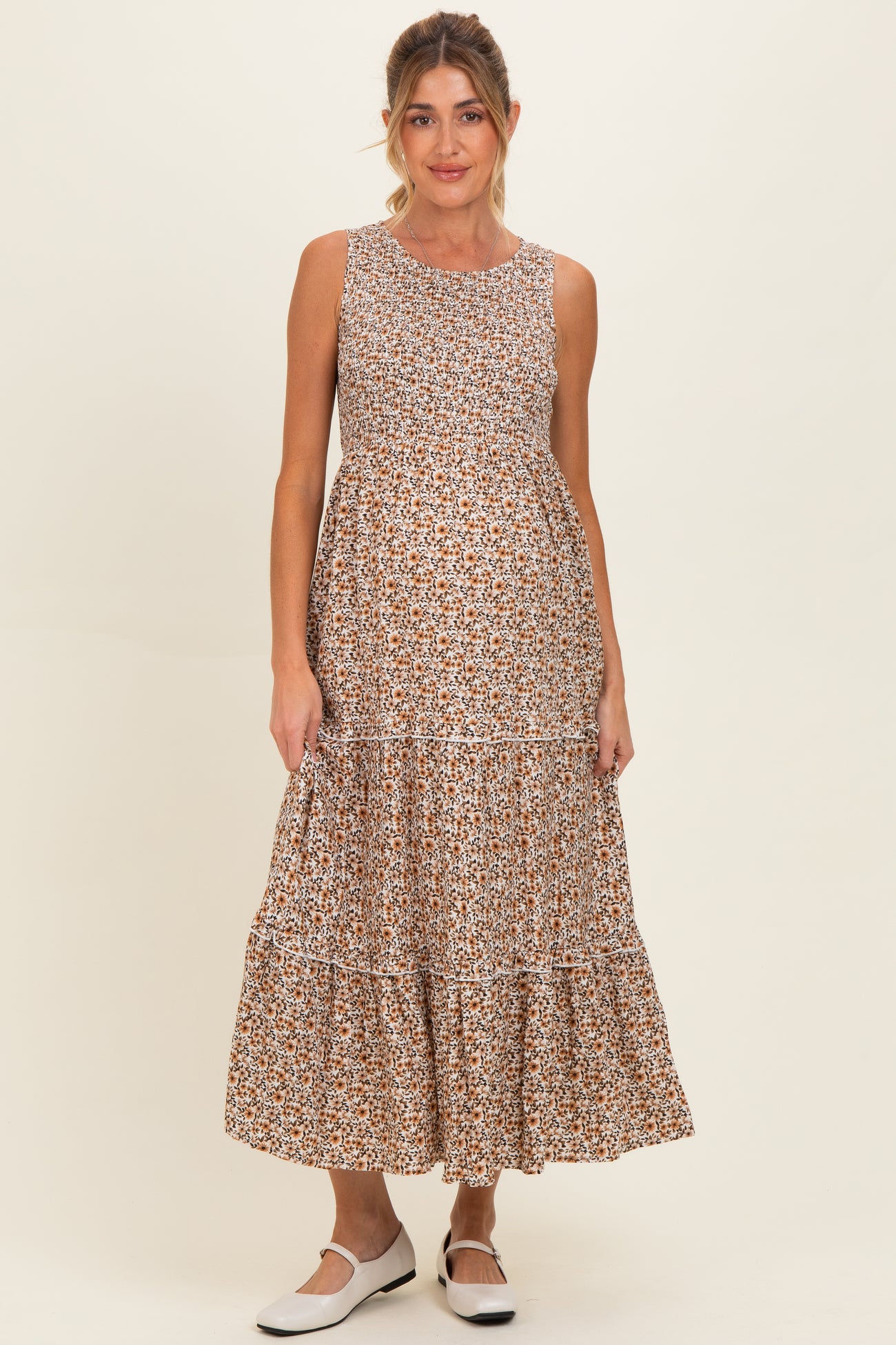 woman wearing a floral print sleeveless maxi maternity dress with a tiered skirt and a baby bump visible