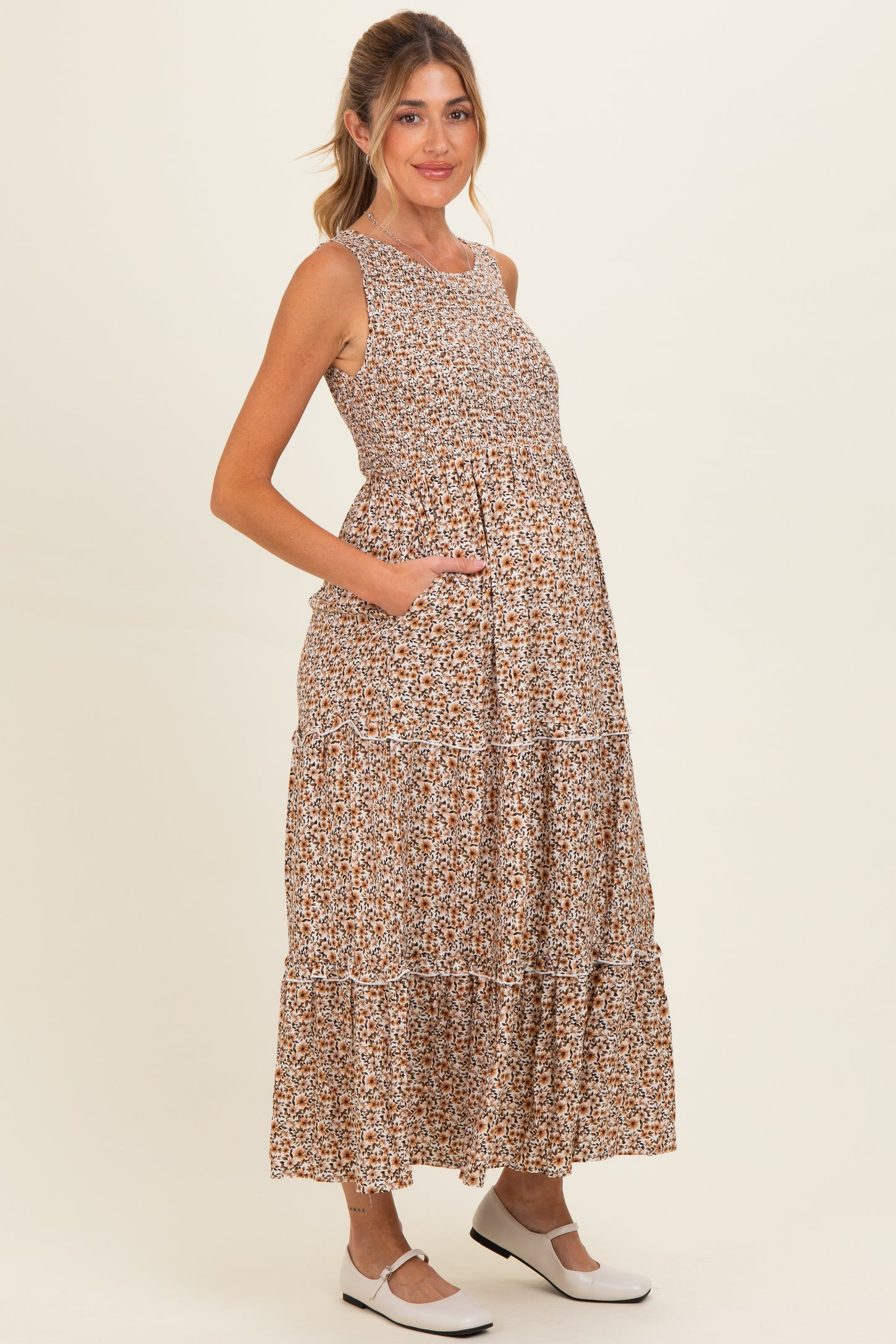 woman wearing a brown floral maternity maxi dress with pockets and a baby bump visible