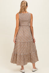 woman wearing a sleeveless brown floral maternity maxi dress with a tiered hem, seen from the back