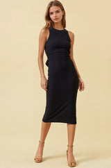 woman wearing a black ribbed midi dress with a sleek fit and side slit, paired with tan high-heeled sandals