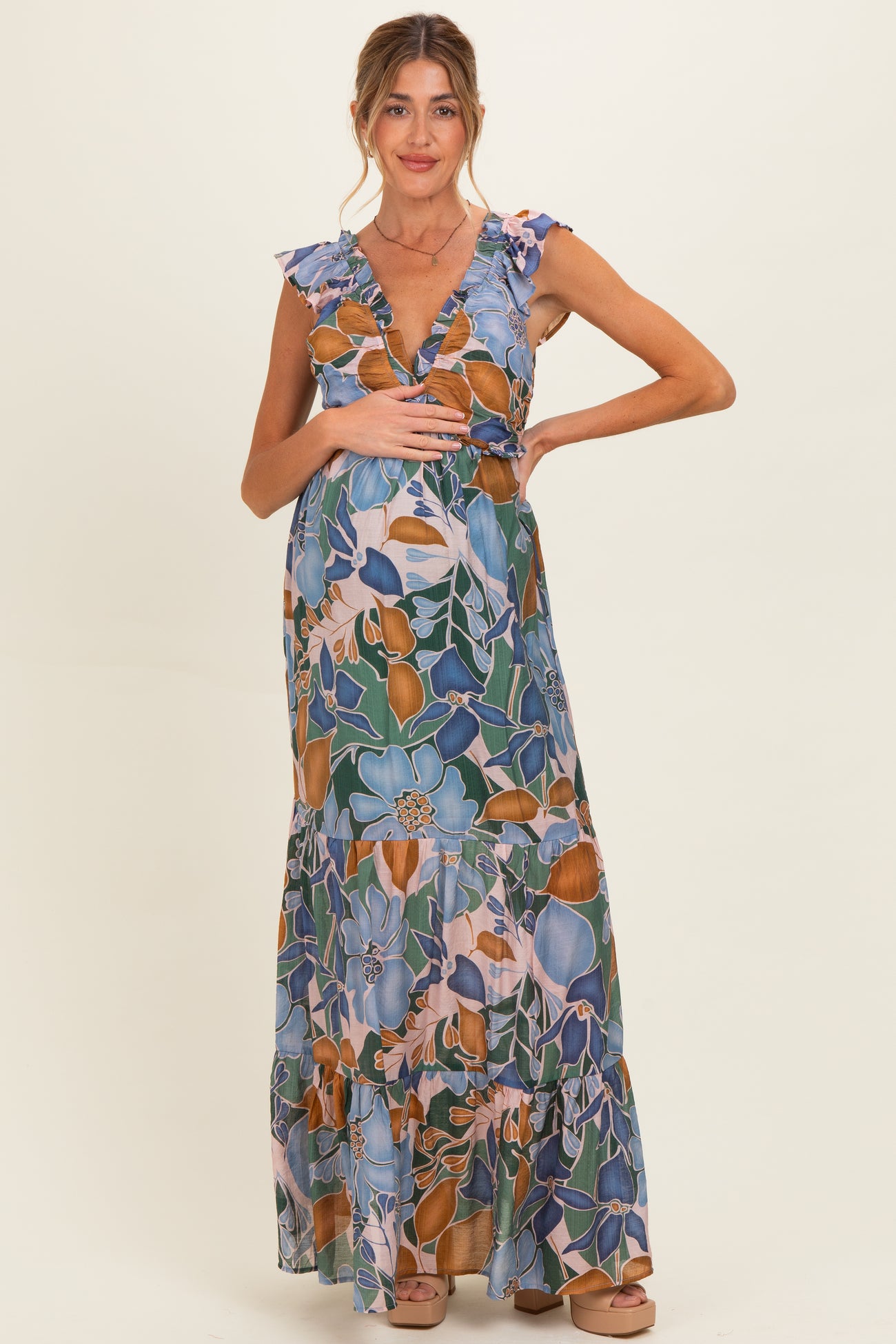 woman wearing a floral maternity maxi dress with ruffled sleeves and holding her baby bump