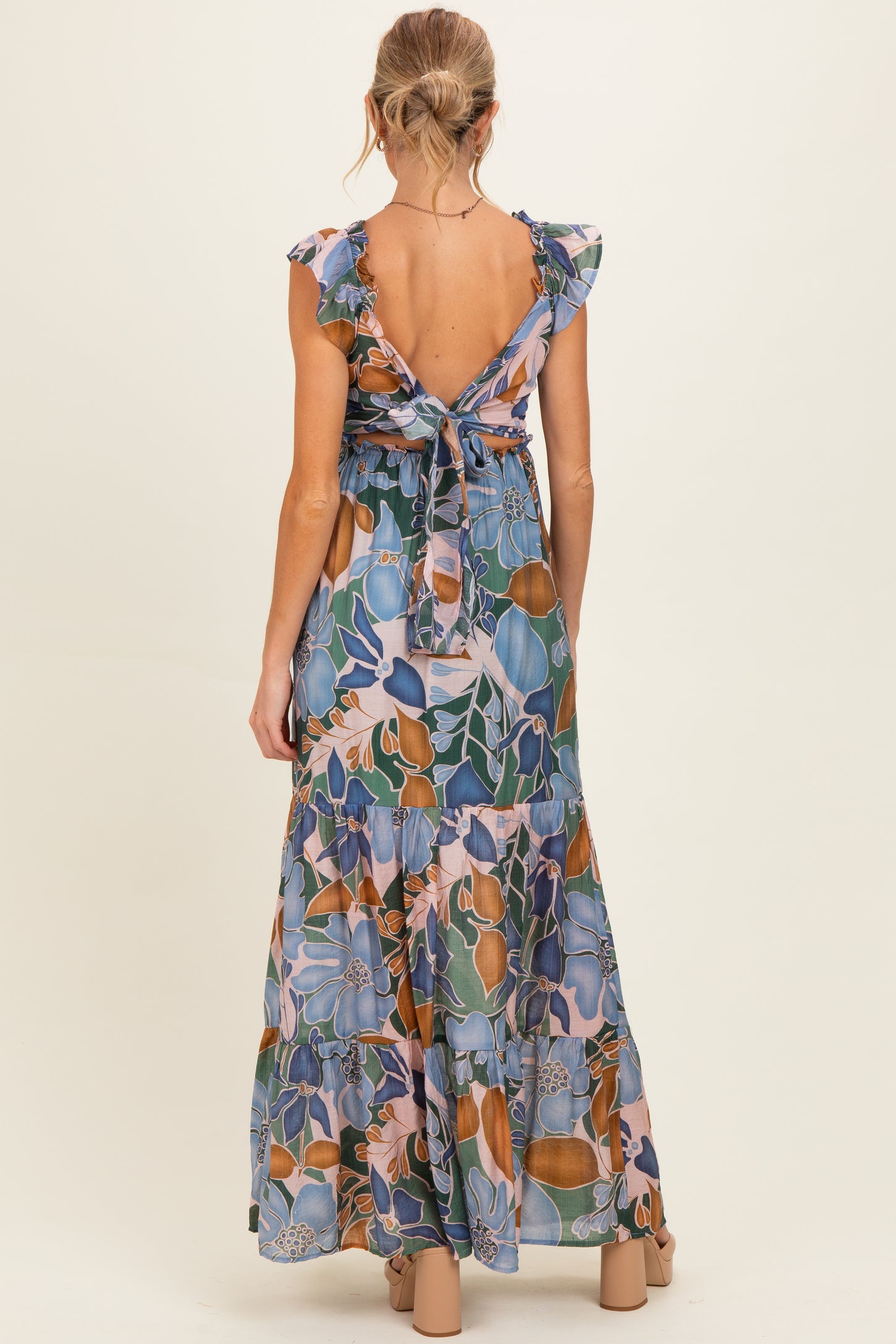 woman wearing a floral print maternity maxi dress with ruffled sleeves and tied back detail