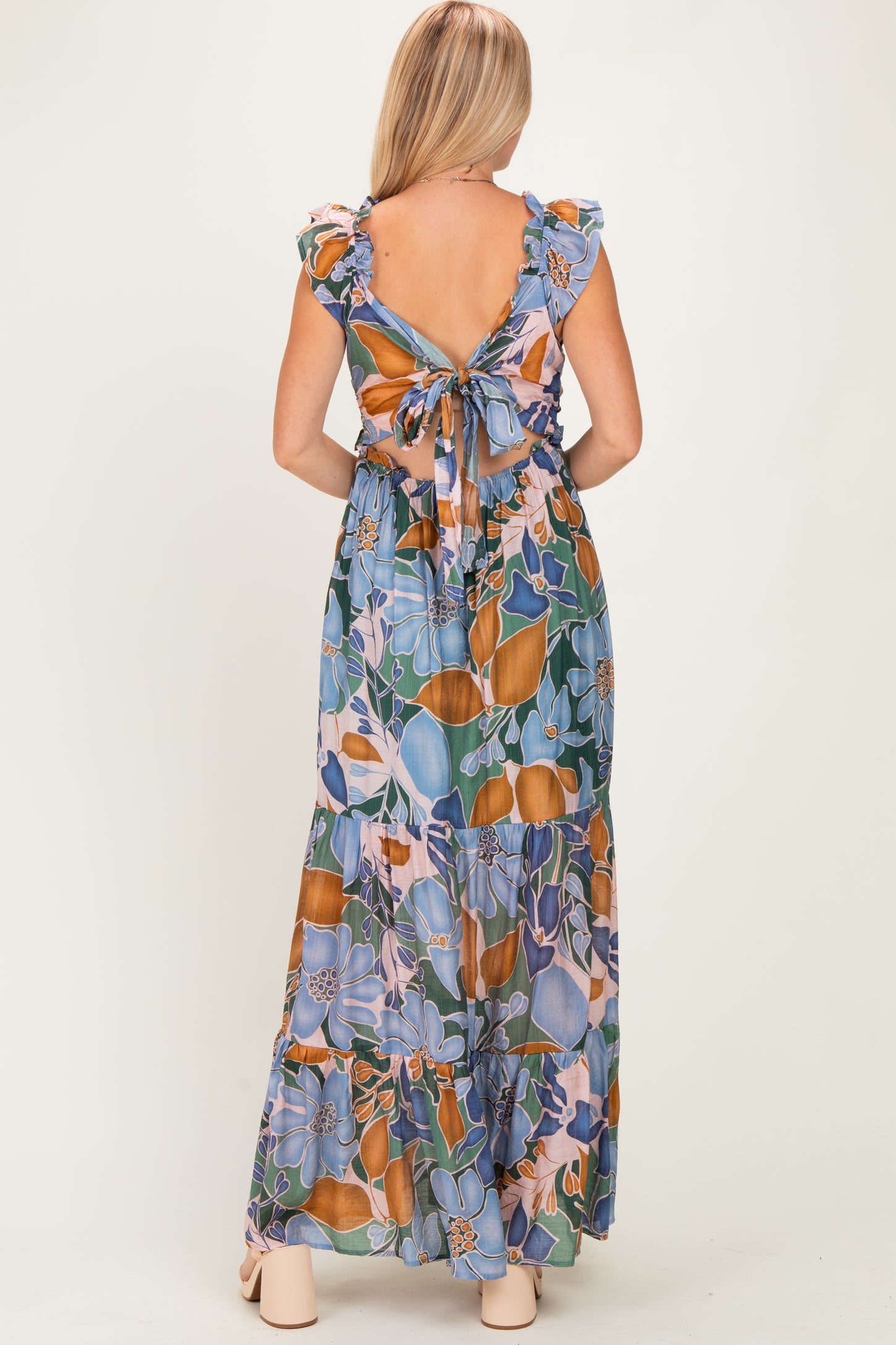 woman wearing a floral patterned maxi dress with a tie back and ruffled sleeves, shown from the back