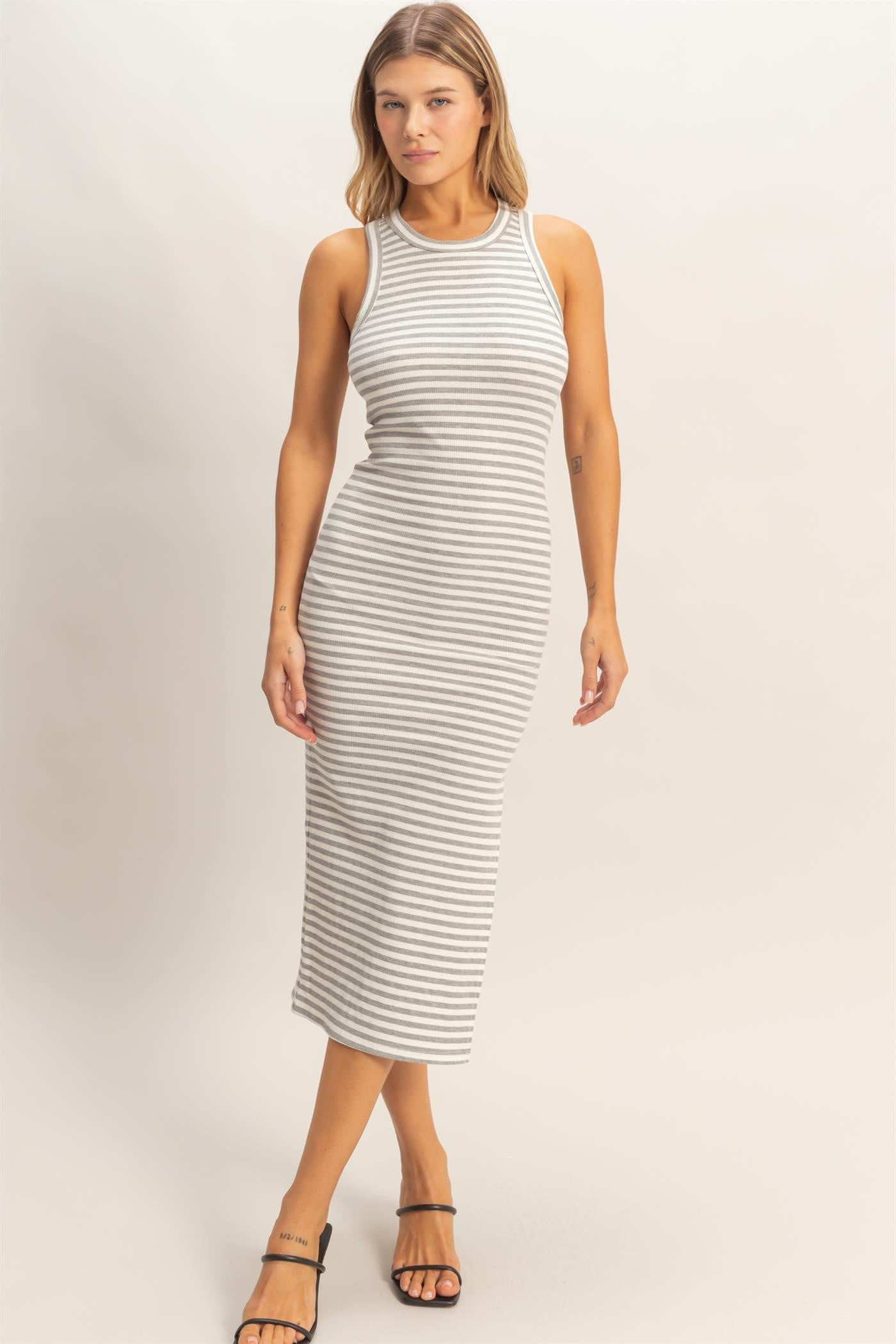 woman wearing a gray and white striped midi tank dress with a fitted silhouette and side slit