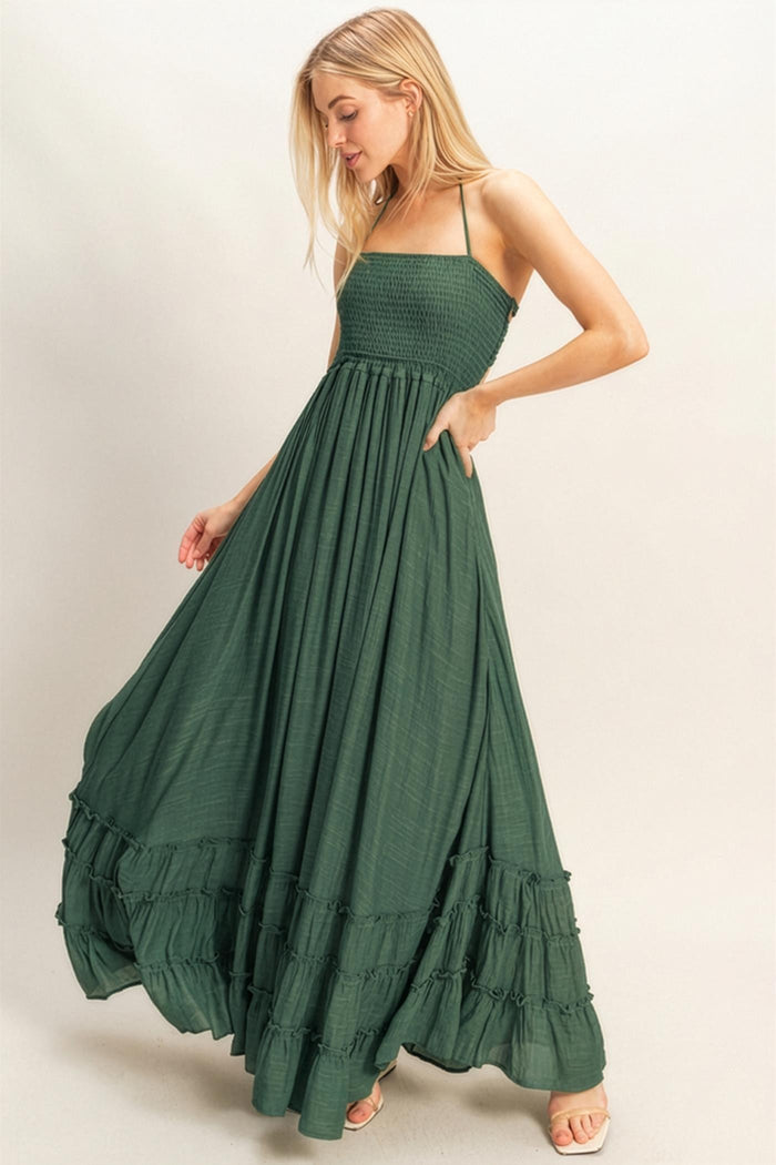 woman wearing a dark green maxi dress with a smocked bodice and tiered ruffle hem